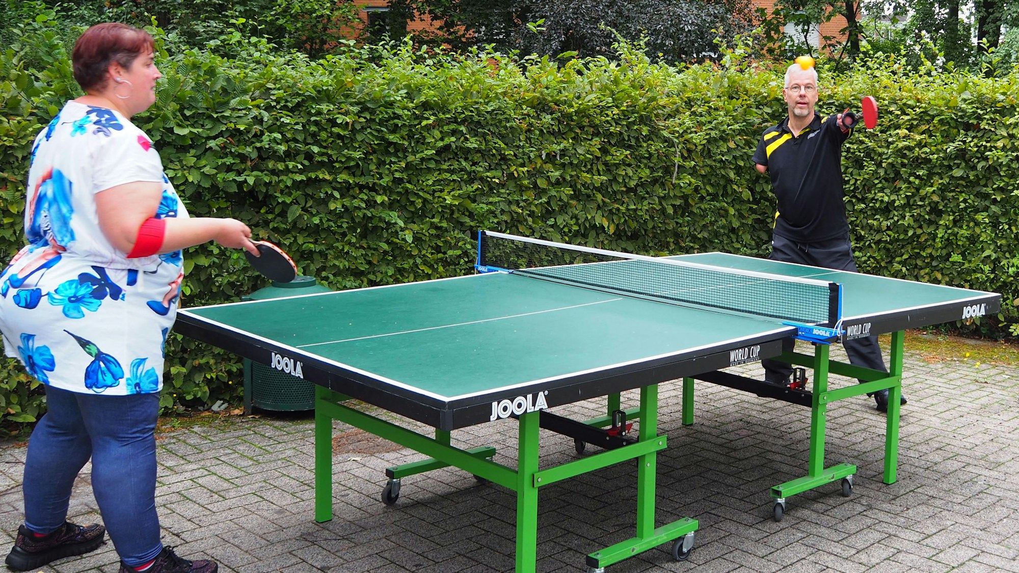 Ein Mann mit verkürzten Armen und eine Frau spielen Tischtennis.