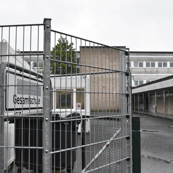 Hinter einem Zaun steht das Schild Gesamtschule. Es weist auf den Haupteingang des Standorts Rosbach hin.