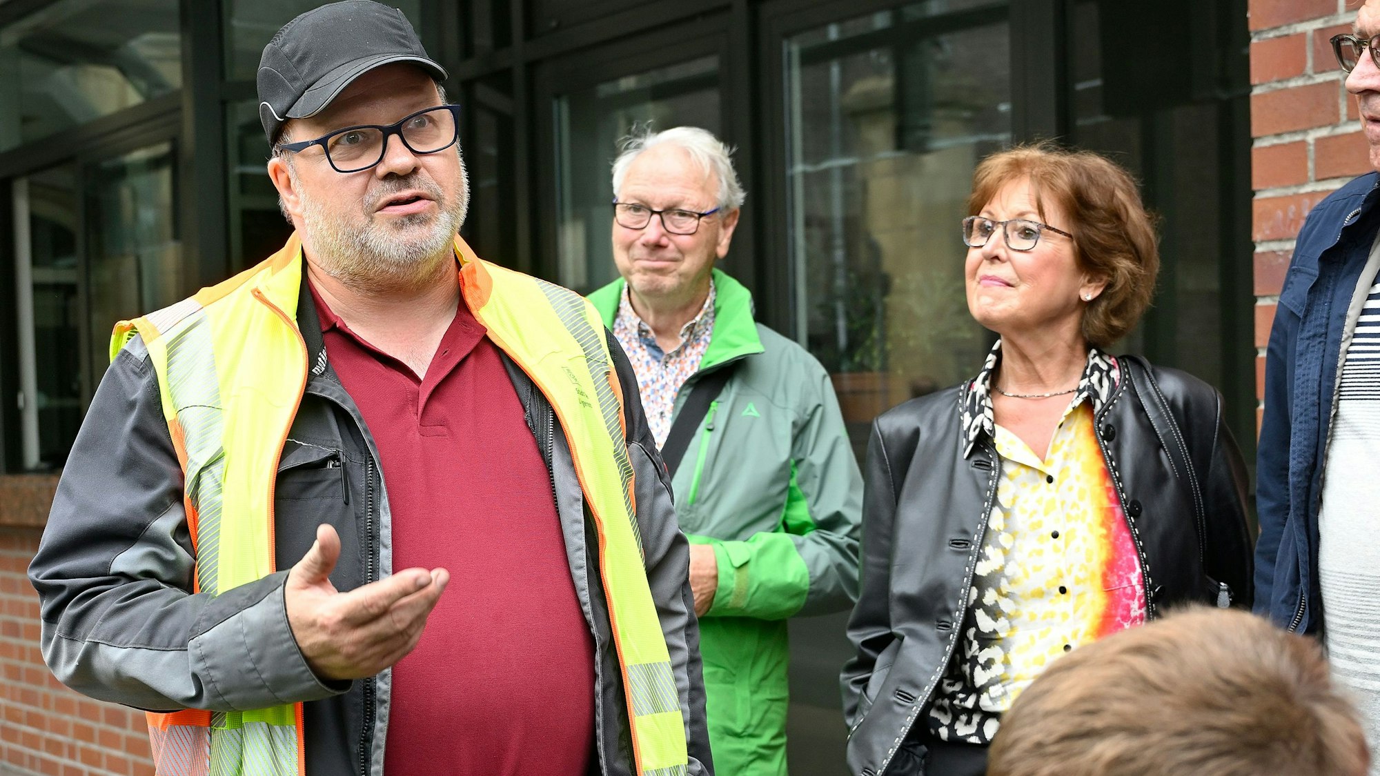 Ein Mann in Warnweste erklärt Menschen etwas.