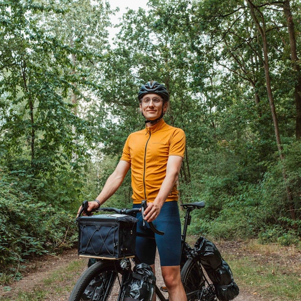 Ein junger Mann sitzt auf einem Fahrrad mit Packtaschen