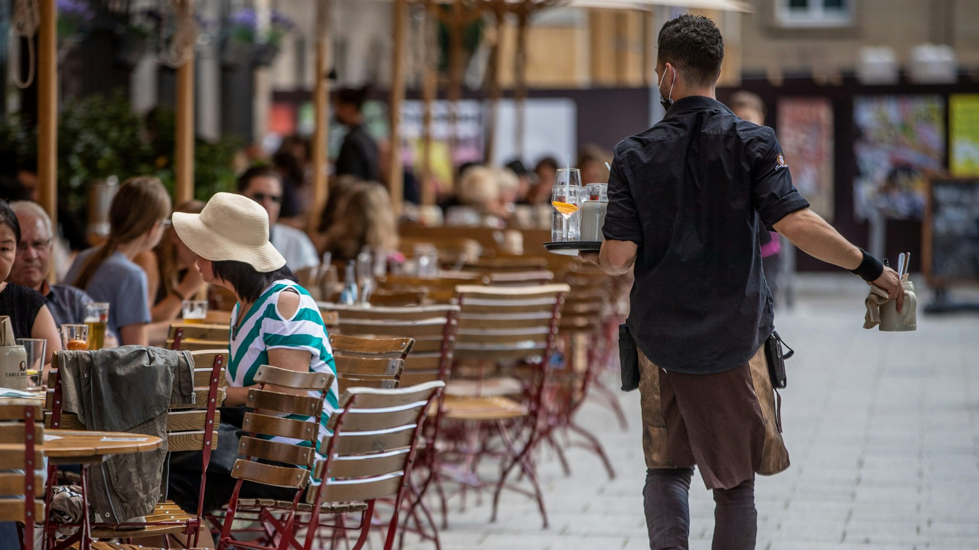 Eine Servicekraft bedient im Außenbereich eines Restaurants die Gäste.
