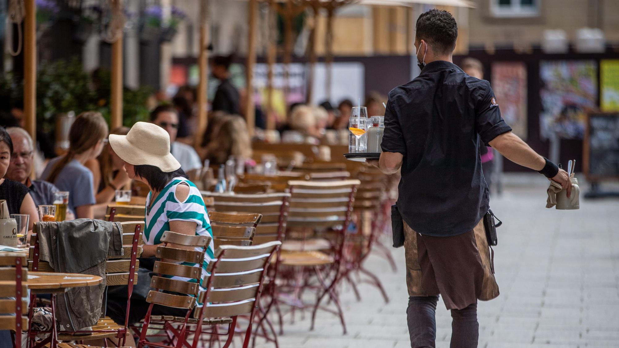 Eine Servicekraft bedient im Außenbereich eines Restaurants die Gäste.