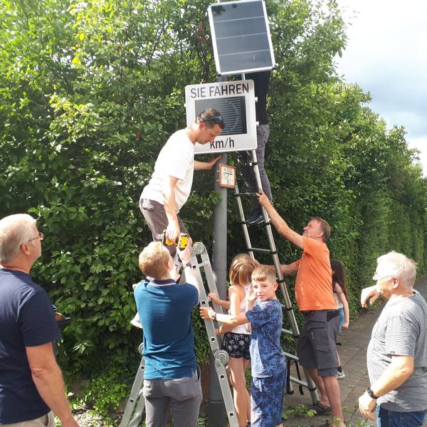Freiwillige Helfer montierten mit vereinten Kräften die neue Tempo-Infotafel an der Longericher Straße.