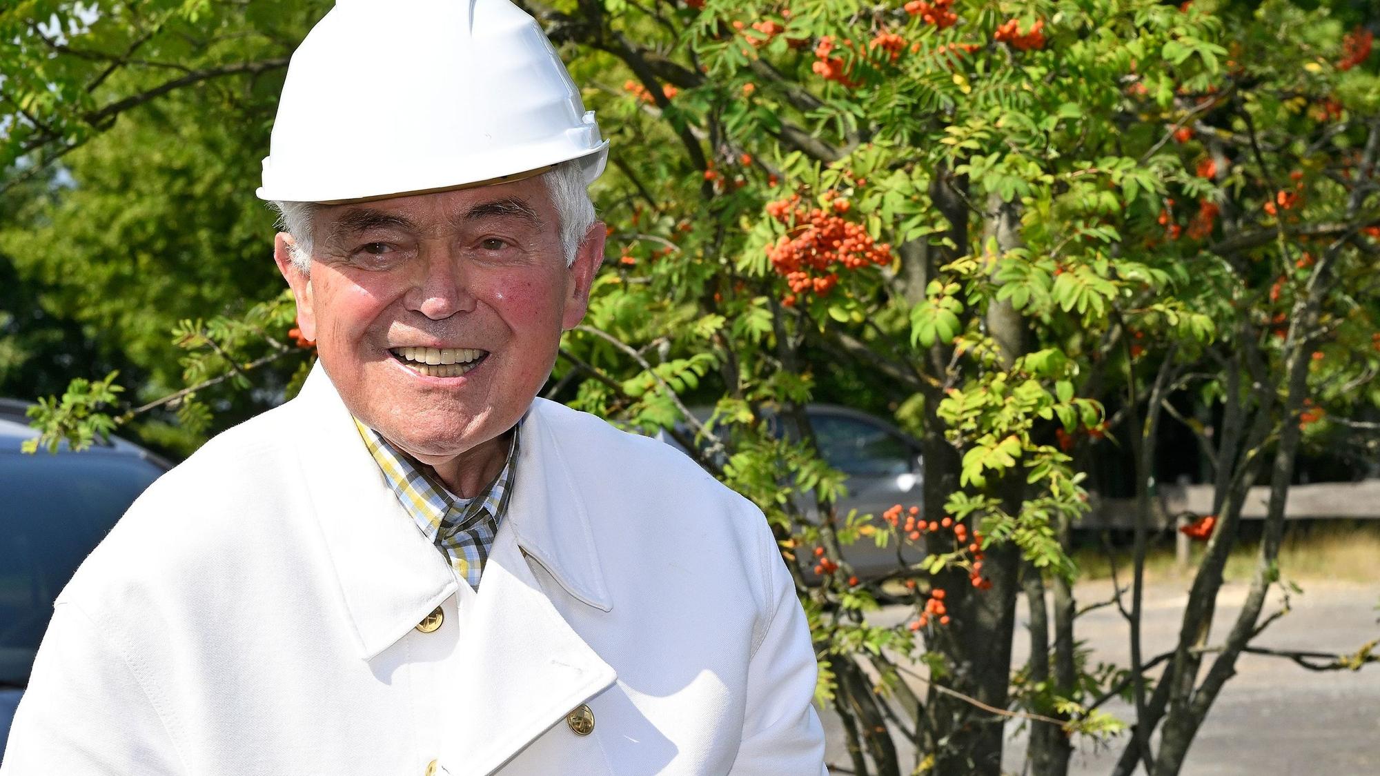 Sigfried Reimann steht am Bergbaurevier auf dem Lüderich und trägt einen weißen Bergmannshelm.