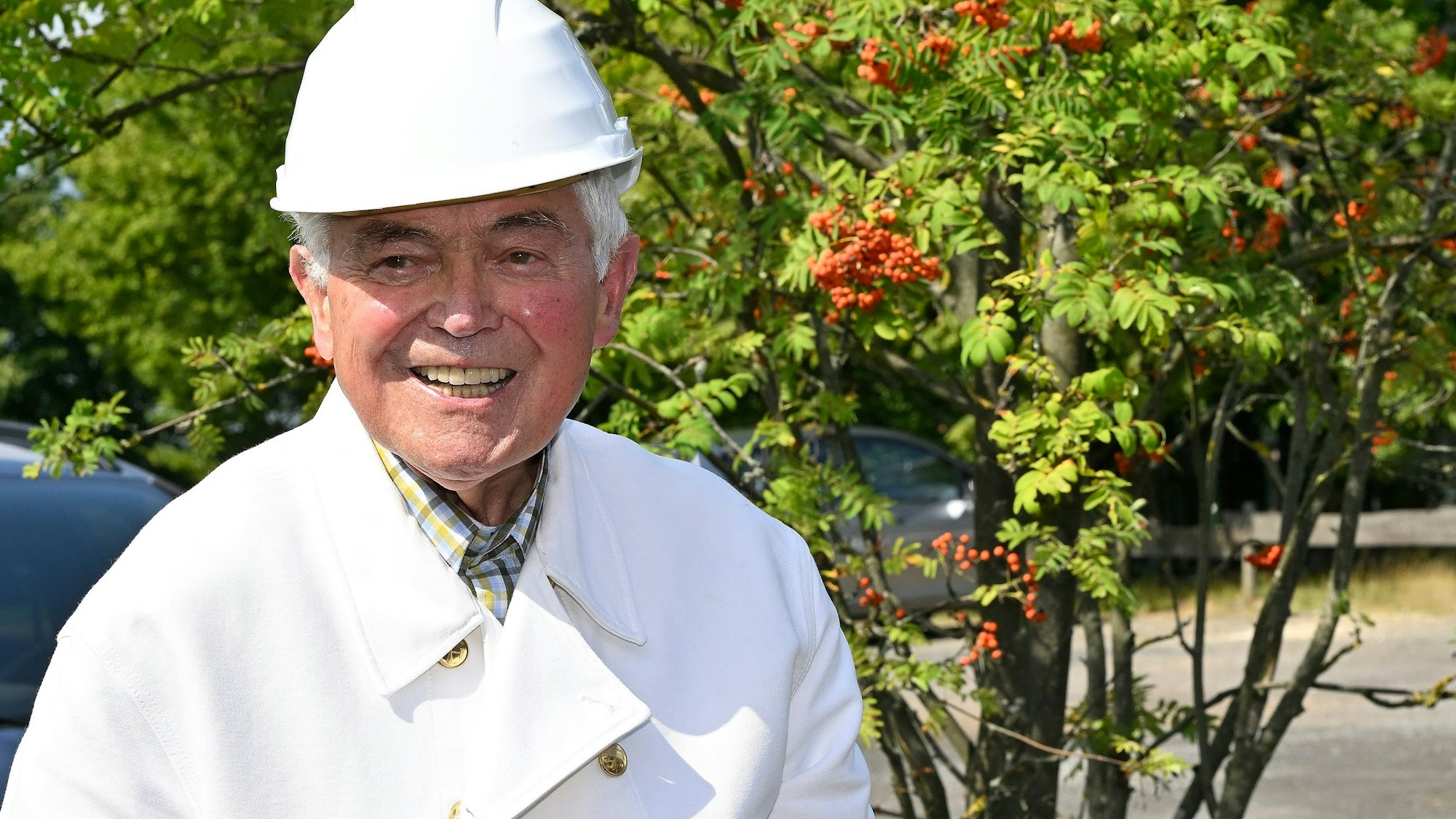 Sigfried Reimann steht am Bergbaurevier auf dem Lüderich und trägt einen weißen Bergmannshelm.