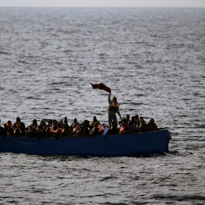 Geflüchtete aus Afrika rufen auf dem Mittelmeer in einem Boot um Hilfe.