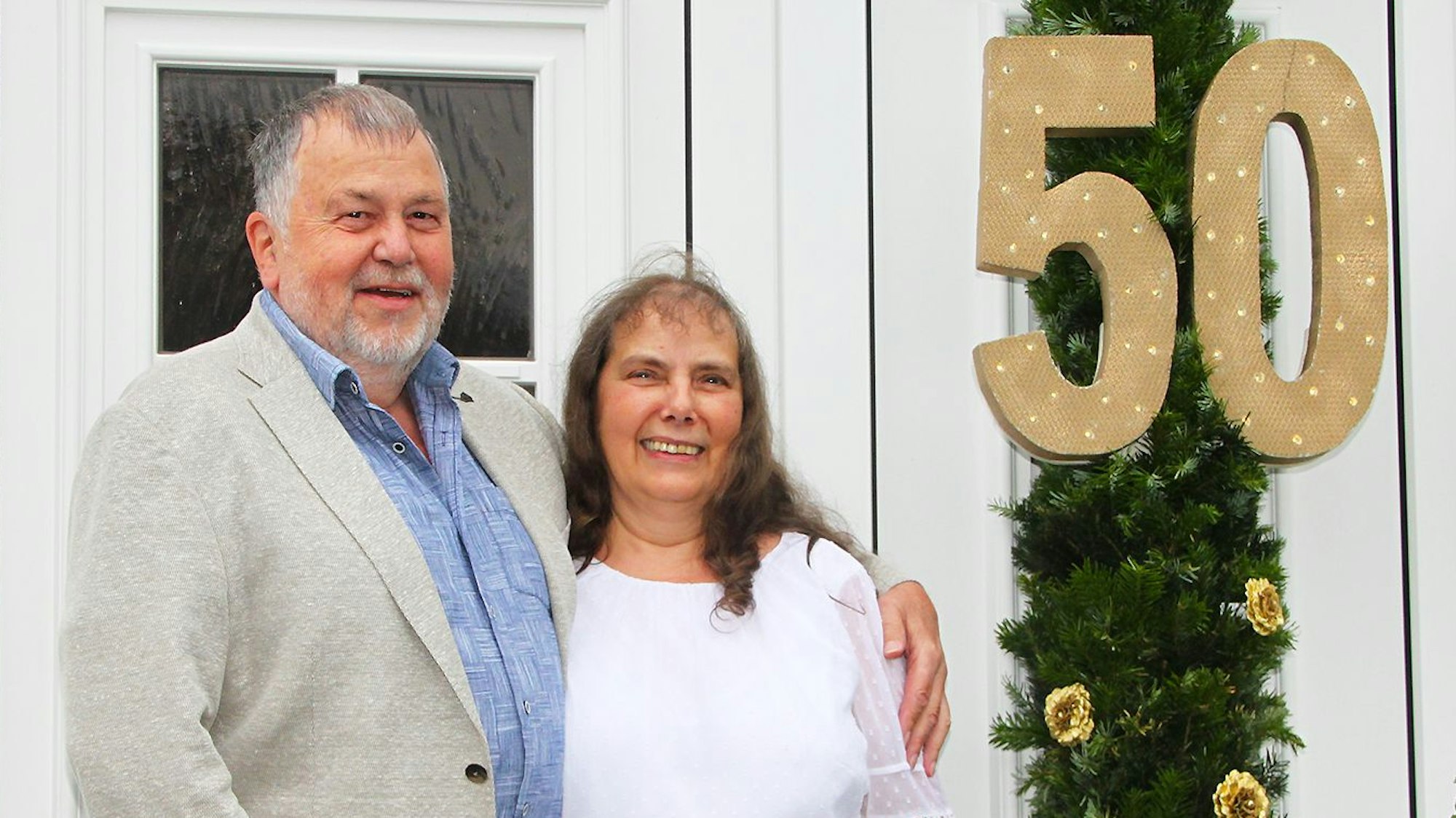 Das Jubelpaar Hans-Werner und Roswitha Schreiber vor der mit einem großen Kranz geschmückten Haustür mit einer großen 50.
