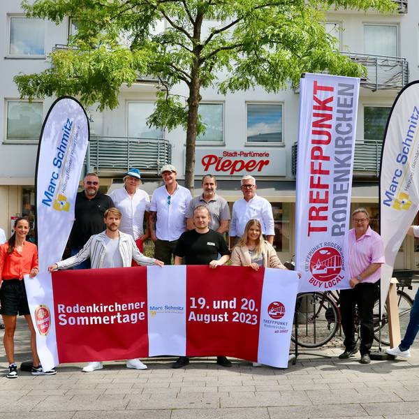 Eine Gruppe von Männern und Frauen präsentiert Werbefahnen auf einem Marktplatz.