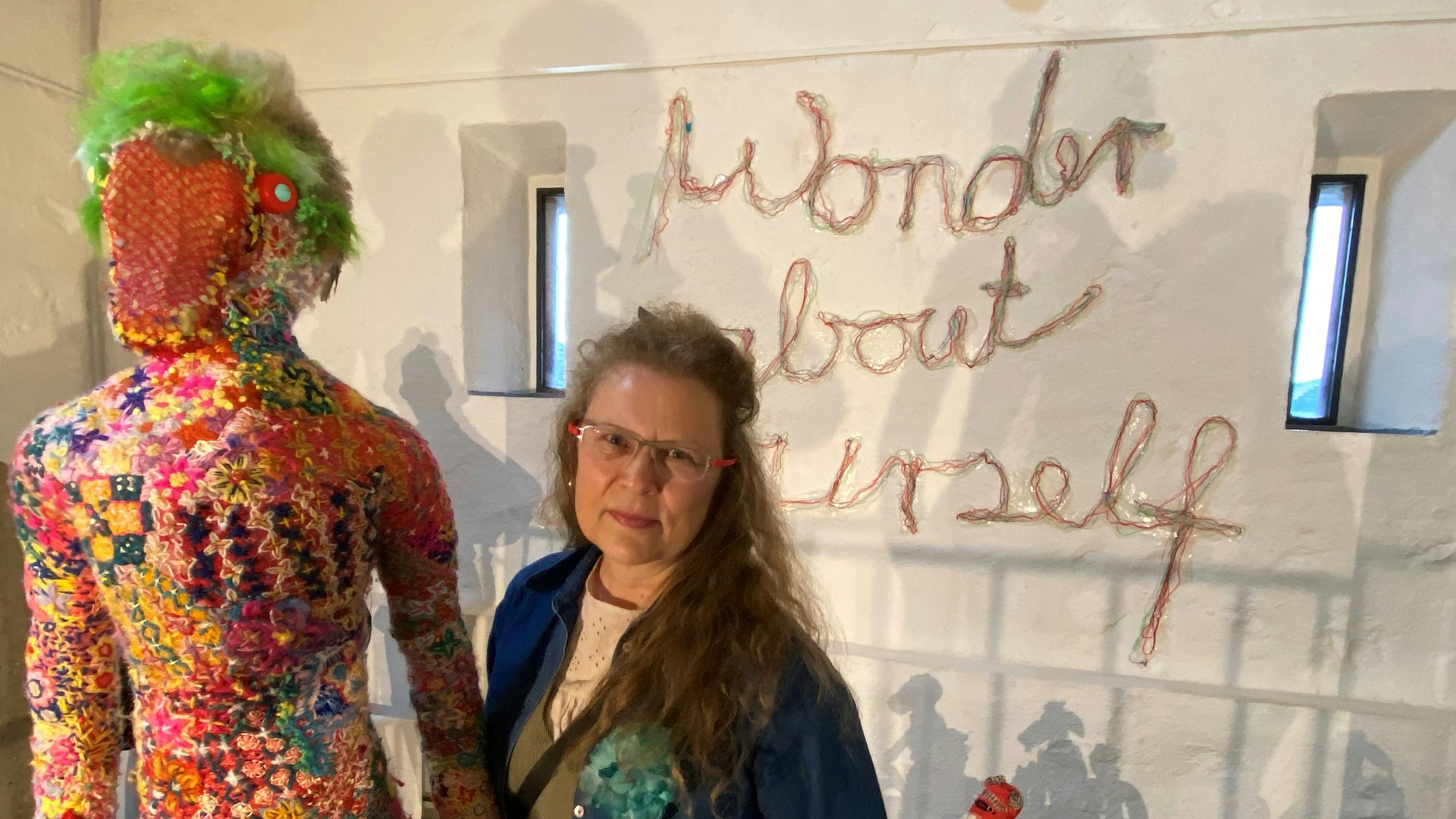Die Künstlerin steht neben einer Figur.