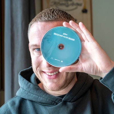 Mo-Torres hält sich eine CD vor ein Auge.