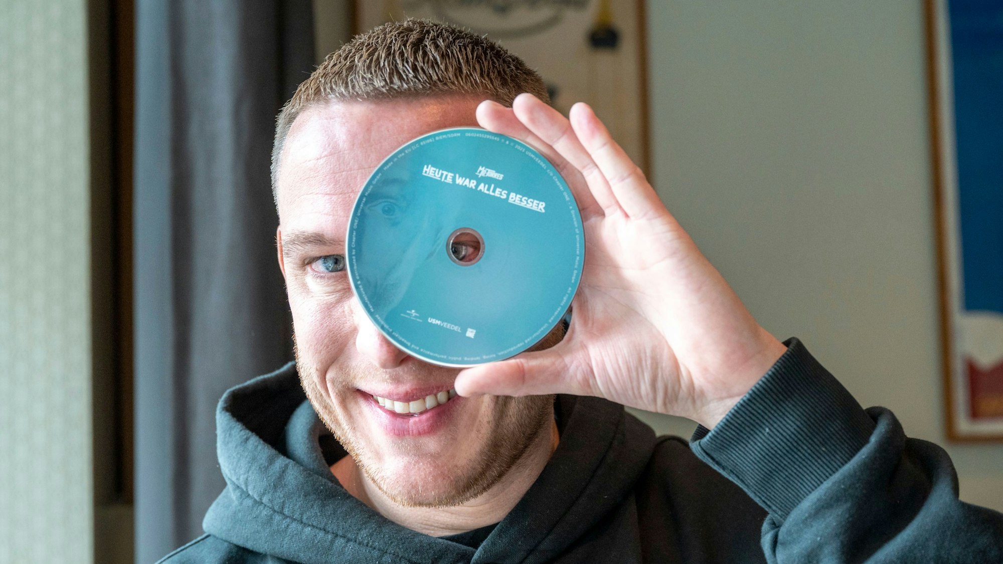 Mo-Torres hält sich eine CD vor ein Auge.