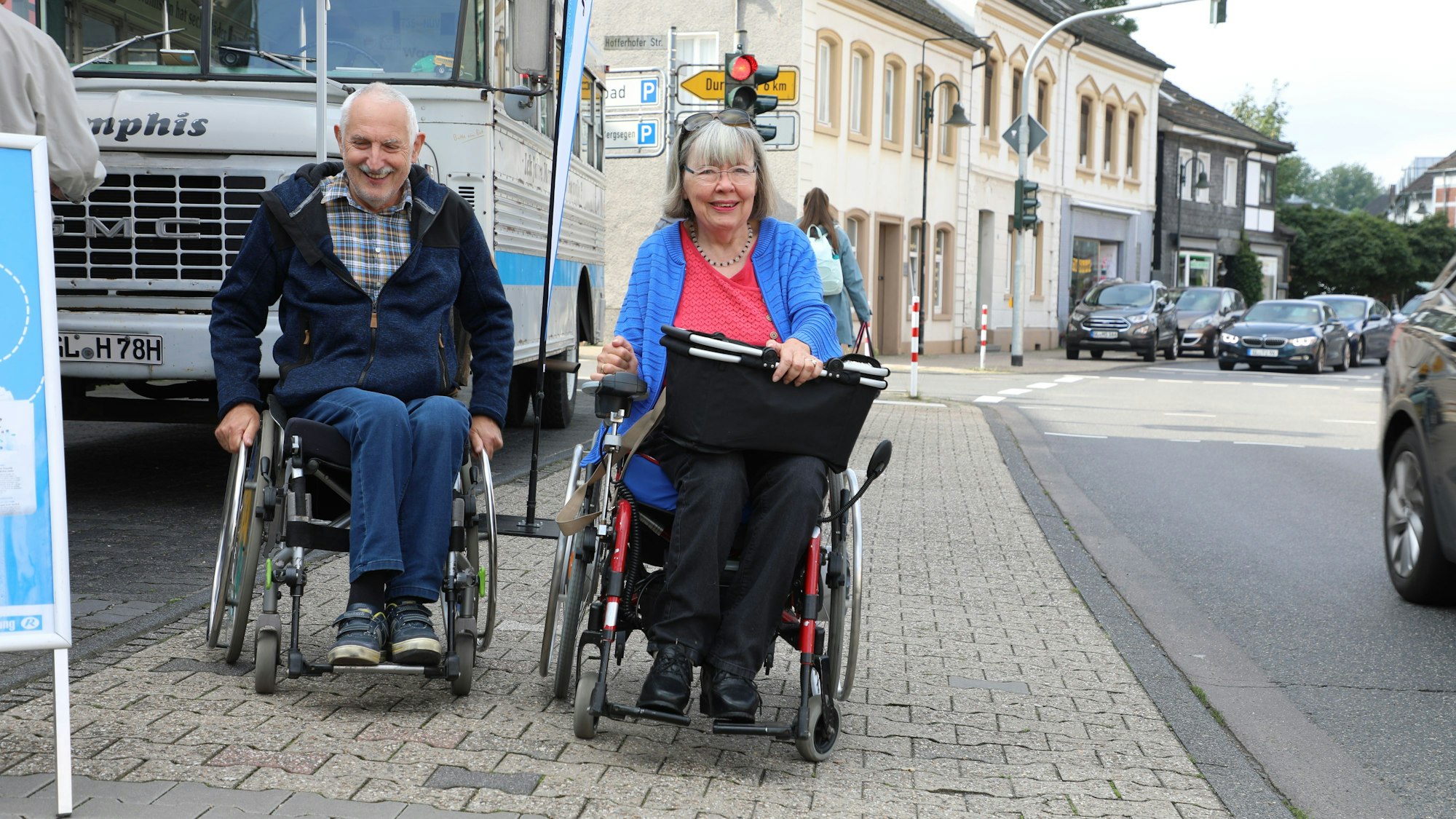 Inge und Jochen Randow fahren mit ihren Rollstühlen über den Gehweg der Hauptstraße in Rösrath-Hoffnungsthal.
