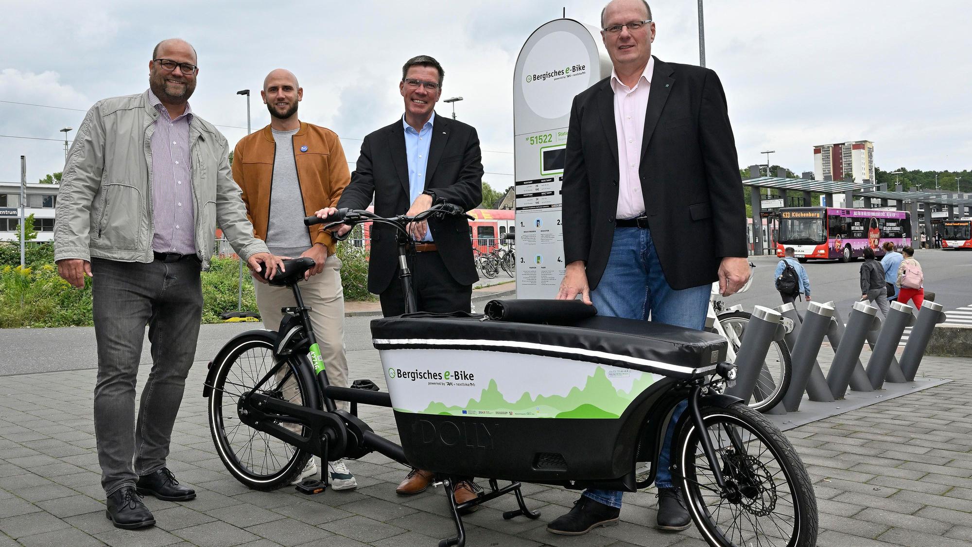 Vier Männer präsentieren ein neues E-Lastenrad am Bergisch Gladbacher S-Bahnhof.