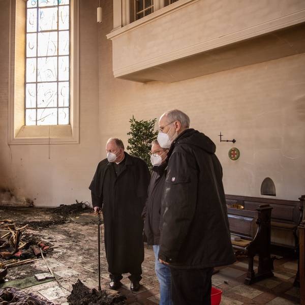 Drei Männer stehen in der durch ein Feuer völlig zerstörten Pfarrkirche Kreuzerhöhung in Wissen an der Sieg.