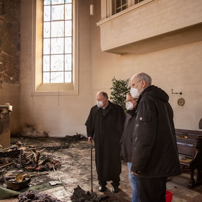 Drei Männer stehen in der durch ein Feuer völlig zerstörten Pfarrkirche Kreuzerhöhung in Wissen an der Sieg.
