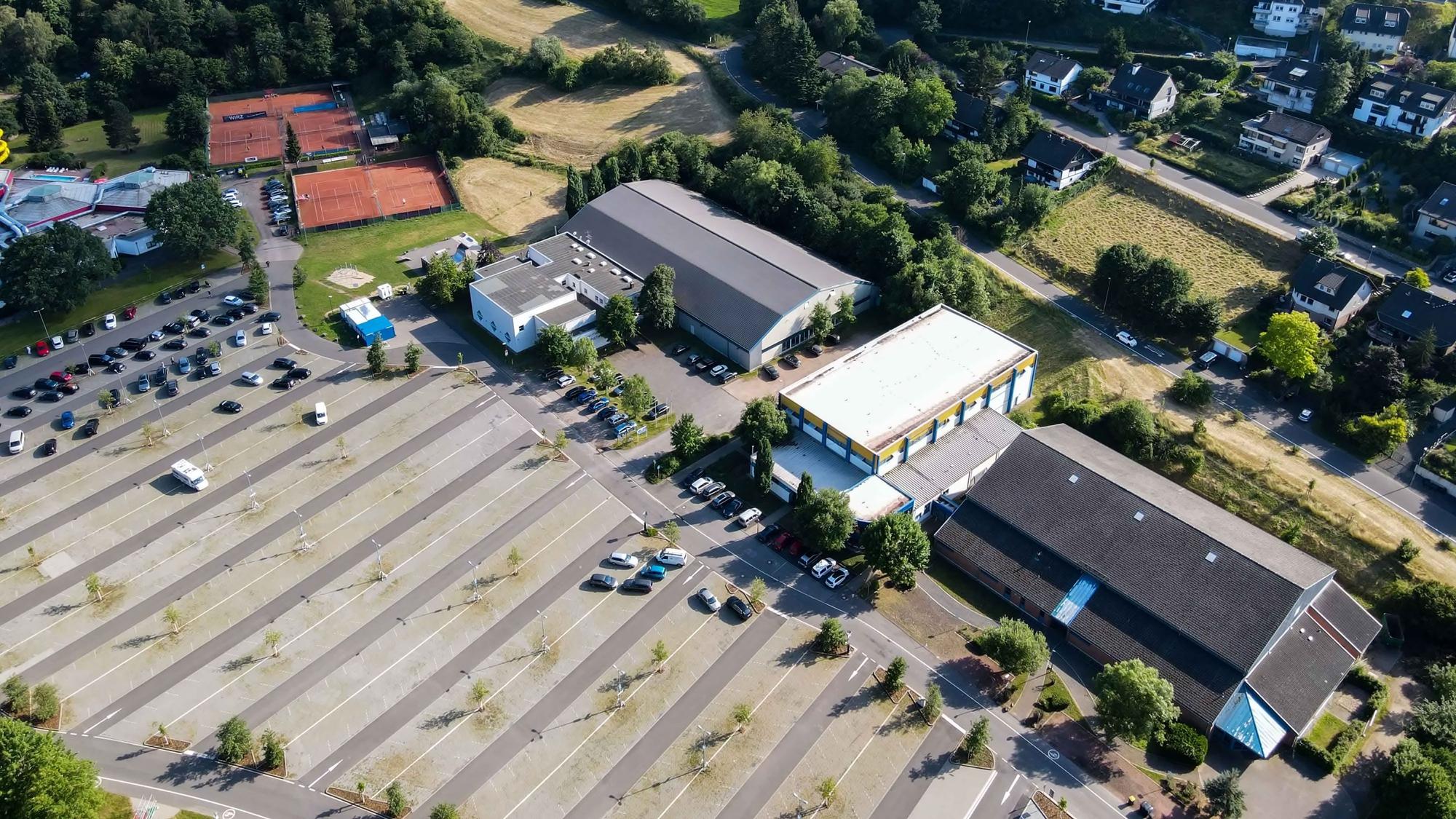 Das Luftbild aus dem Sommer 2022 zeigt den großen Parkplatz im Goldenen Tal und die Sporthallen von Bad Münstereifel sowie die Tennisplätze.
