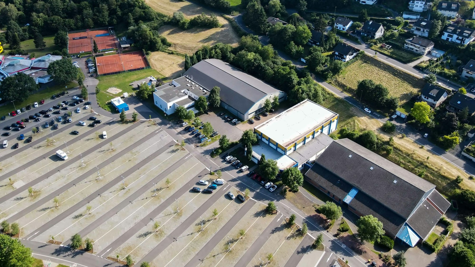 Das Luftbild aus dem Sommer 2022 zeigt den großen Parkplatz im Goldenen Tal und die Sporthallen von Bad Münstereifel sowie die Tennisplätze.