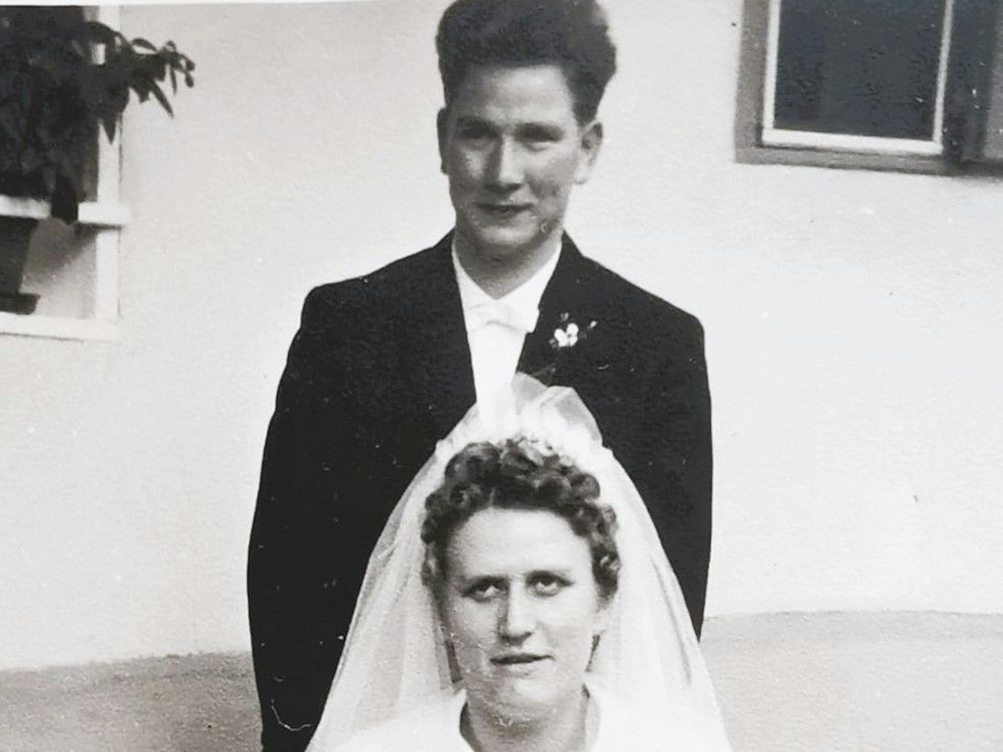 Das Paar - sie in Weiß, er im Anzug - posiert für das Hochzeitsfoto.