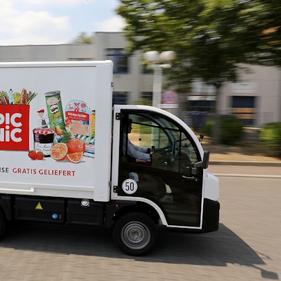 Einer der in die Höhe ragenden Elektro-Vans wird von einem Fahrer gesteuert.