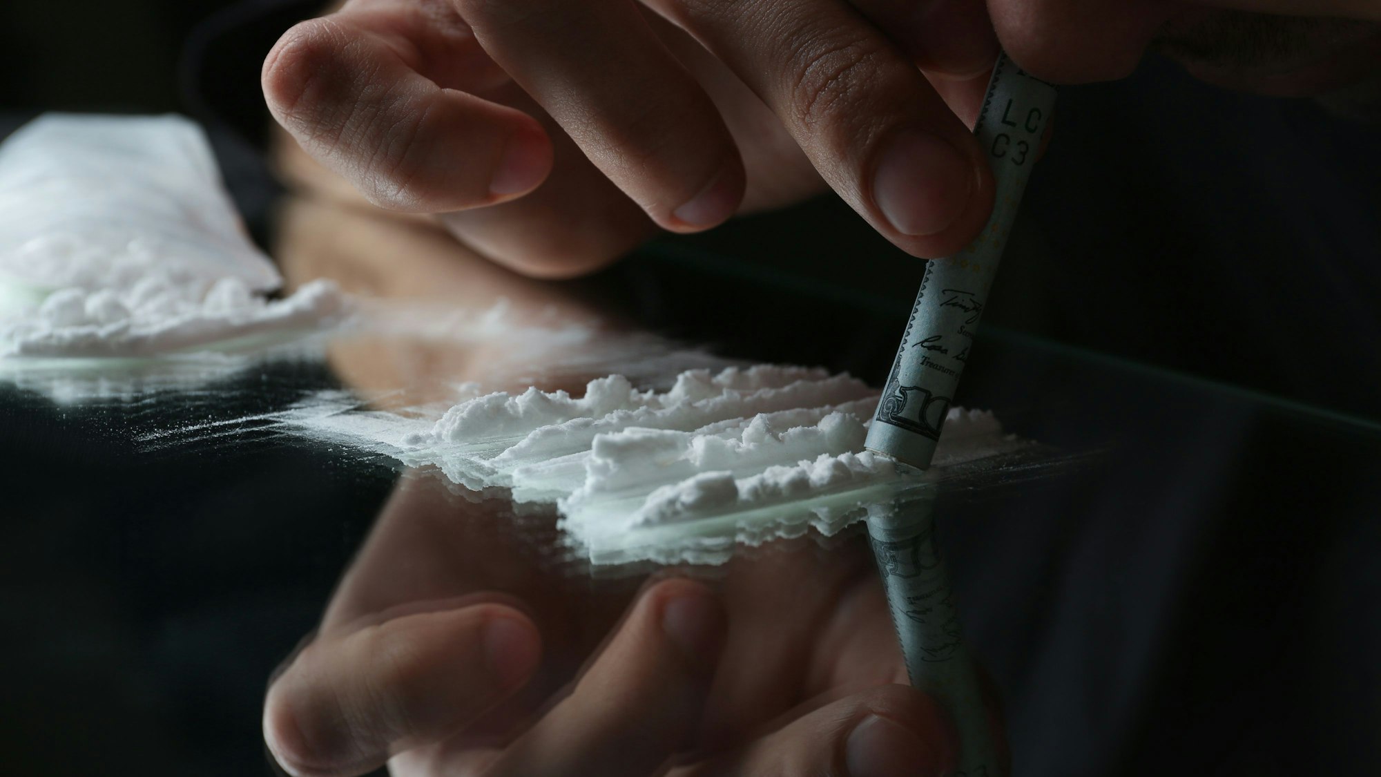 Eine Person zieht eine Line Kokain durch einen Geldschein