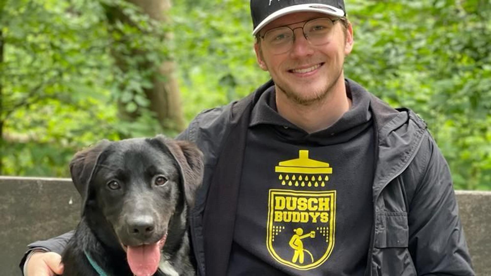 Ein Mann sitzt mit seinem Hund auf einer Bank.