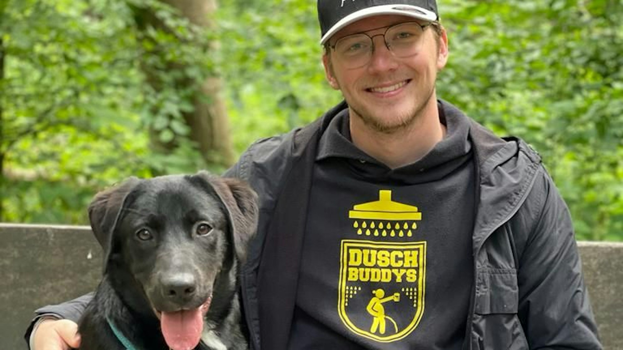 Ein Mann sitzt mit seinem Hund auf einer Bank.