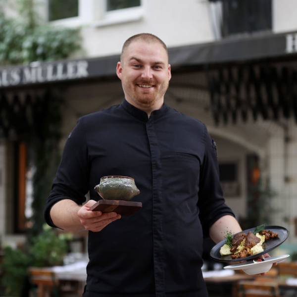 Lasse Hülsmeier steht vor dem Haus Müller und hält drei verschiedene Gerichte in der Hand