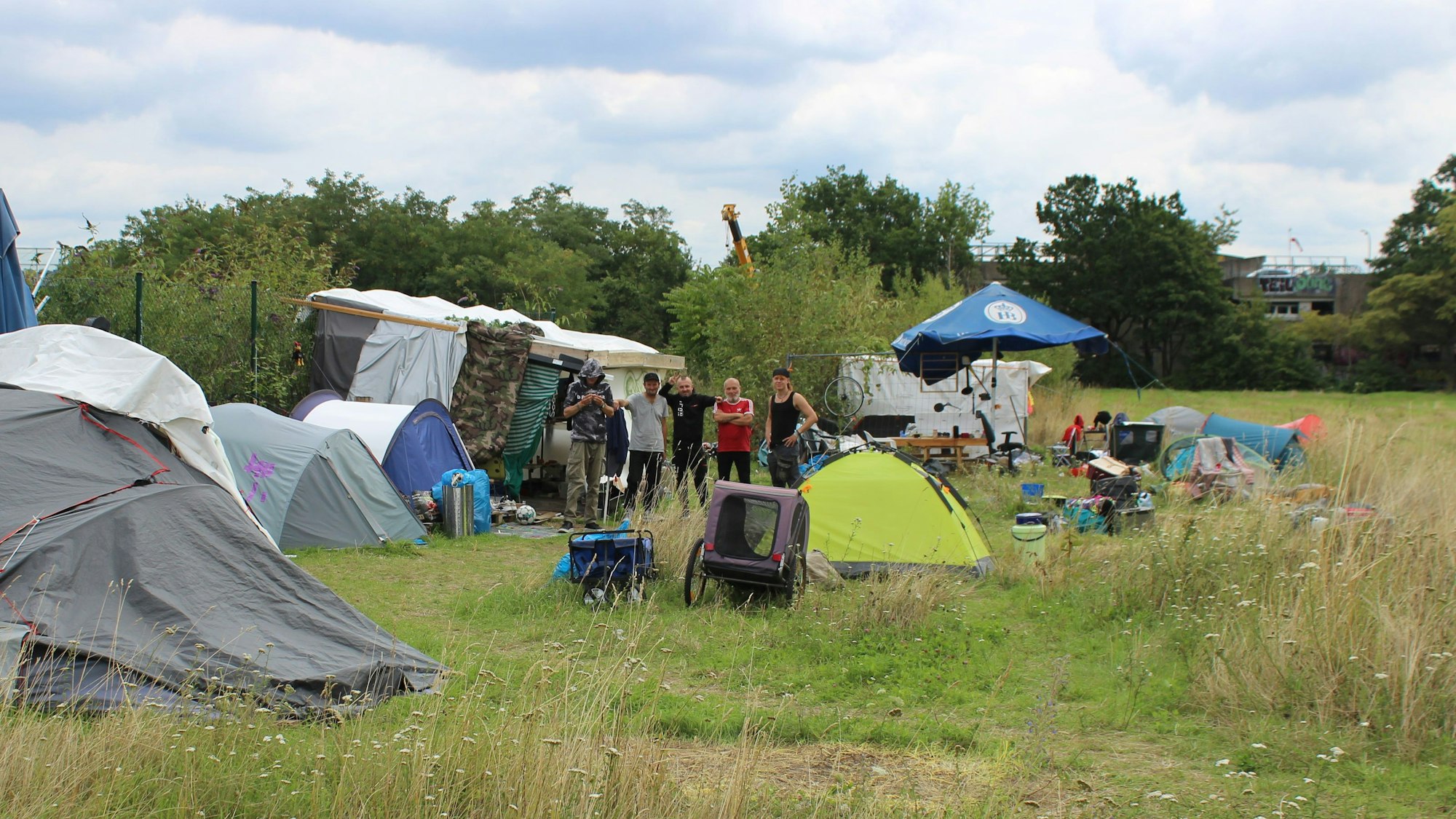 Junge Männer, die vor Zelten stehen.