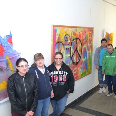 Jugendliche stehen im Gang des Rathauses in Euskirchen. An den Wänden hängen ihre Gemälde.