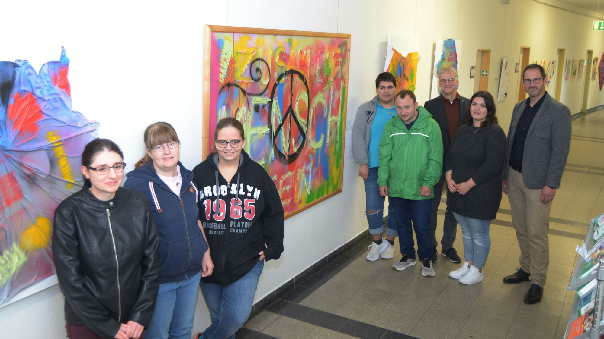 Jugendliche stehen im Gang des Rathauses in Euskirchen. An den Wänden hängen ihre Gemälde.