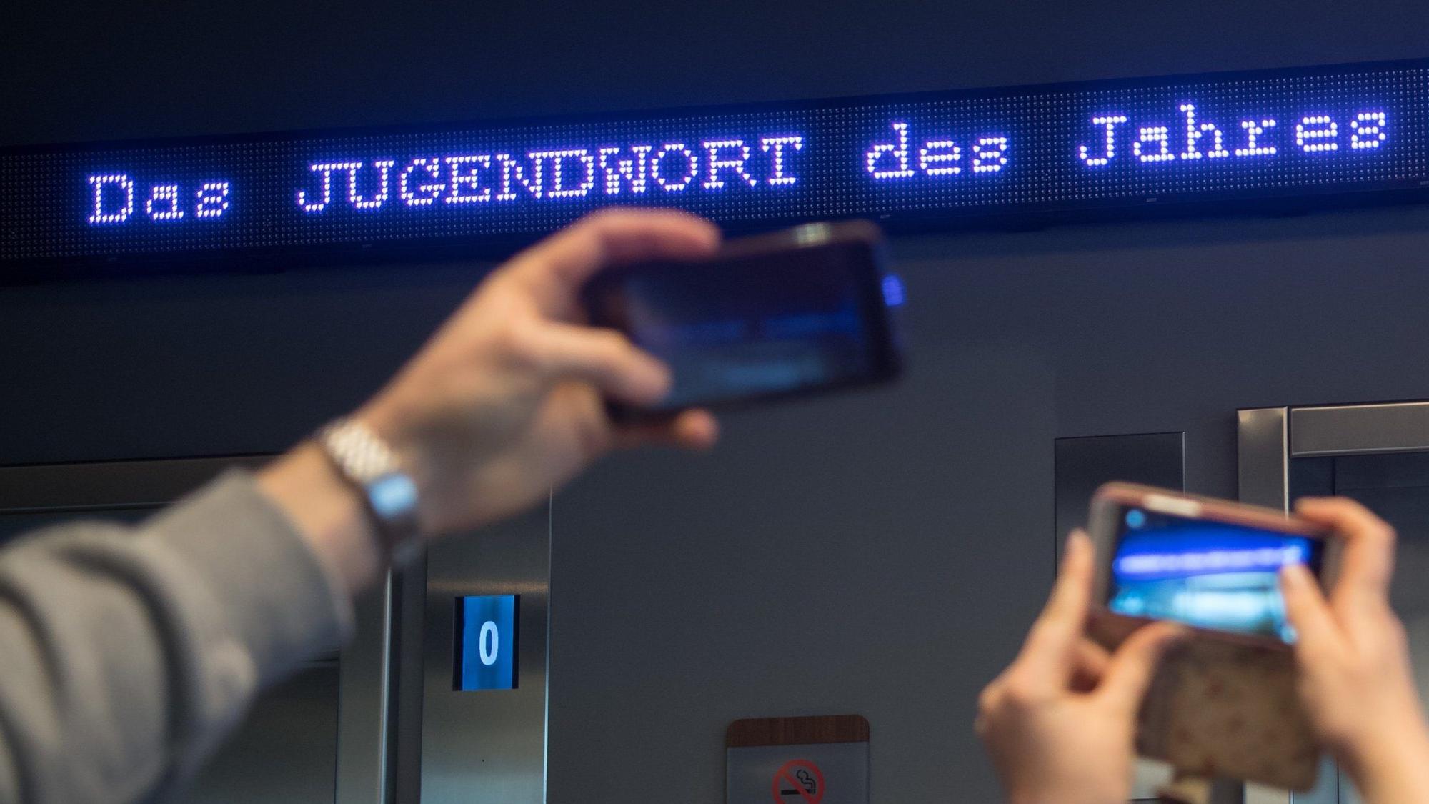 Auf einem Laufband erscheint „Jugendwort des Jahres“ über den digitalen Newsticker eines Hotels (Symbolbild).