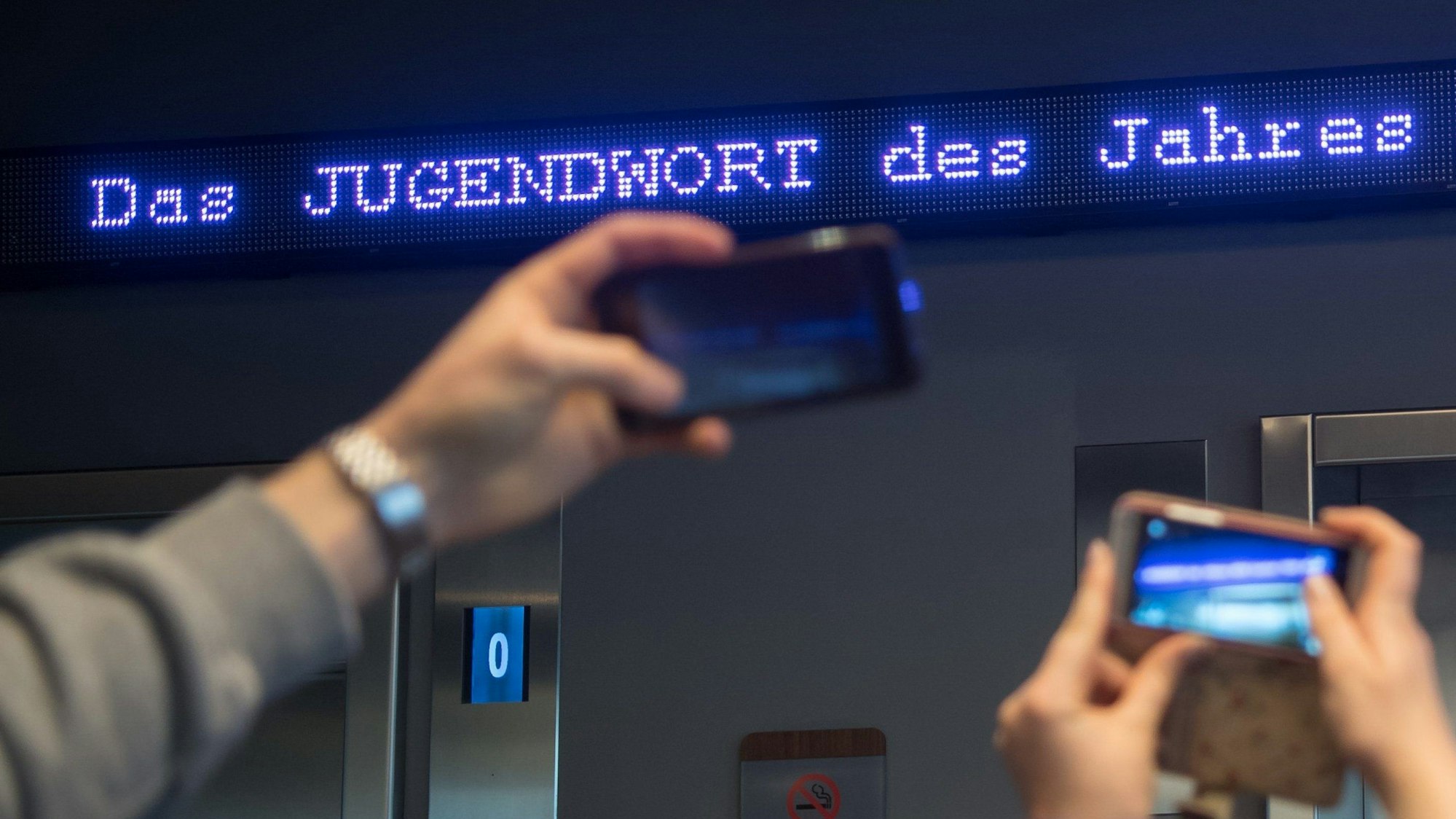 Auf einem Laufband erscheint „Jugendwort des Jahres“ über den digitalen Newsticker eines Hotels (Symbolbild).