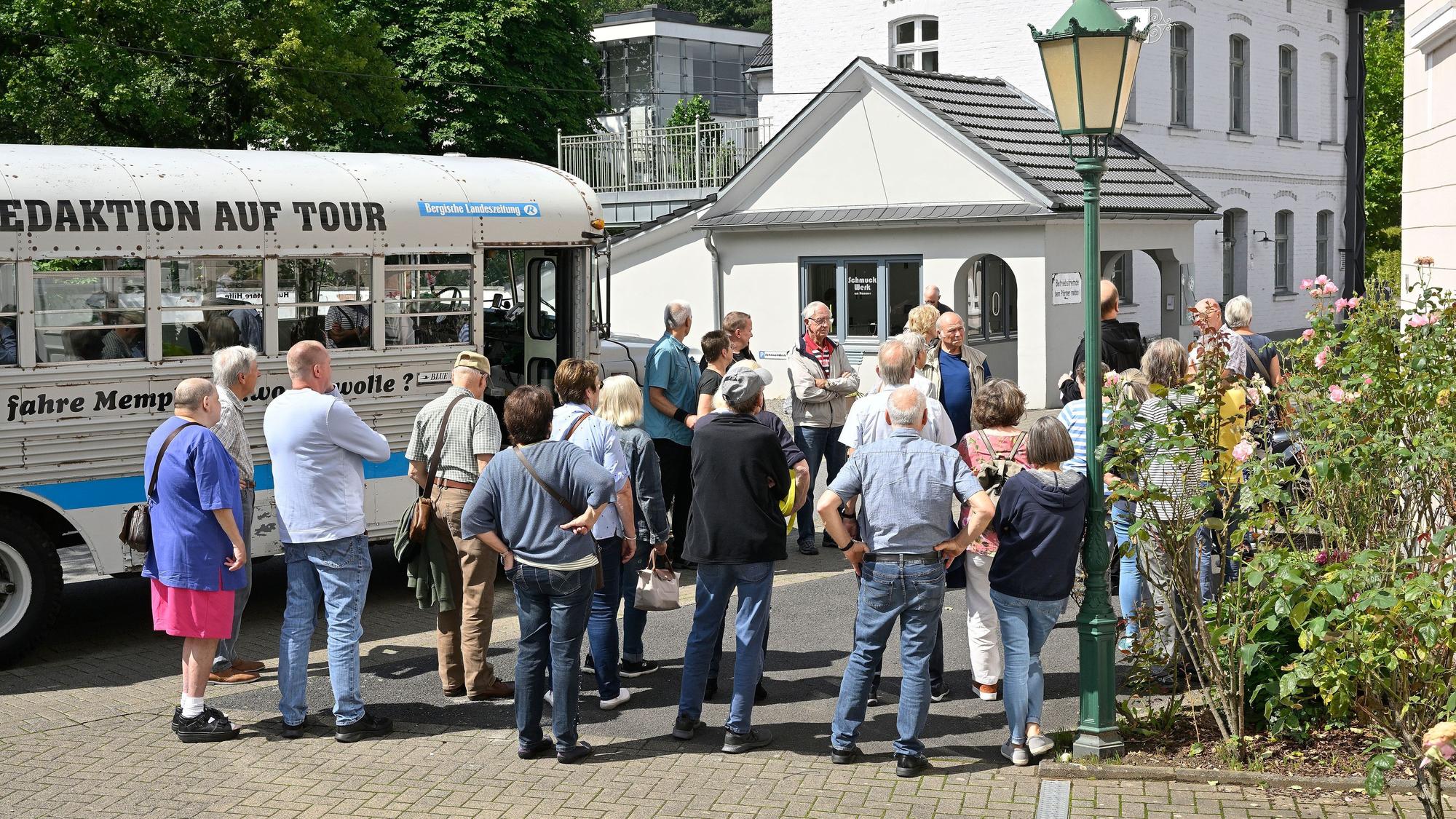 Menschen stehen neben einem historischen Bus in einem historischen Industriegelände.