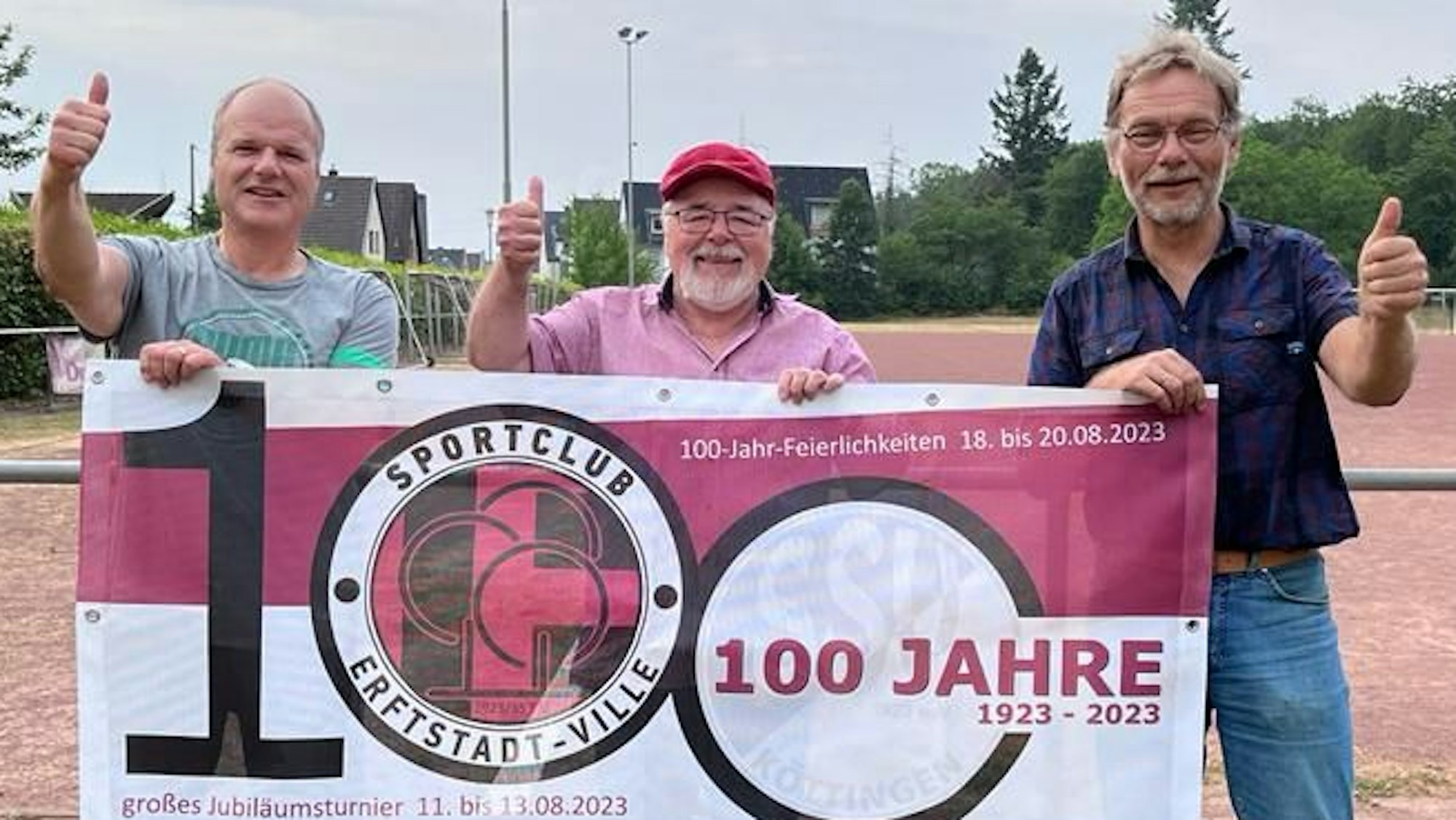 Das Bild zeigt drei Verantwortliche des Vereins. Sie halten ein Banner mit den Logo des Klubs und strecken die Daumen nach oben.
