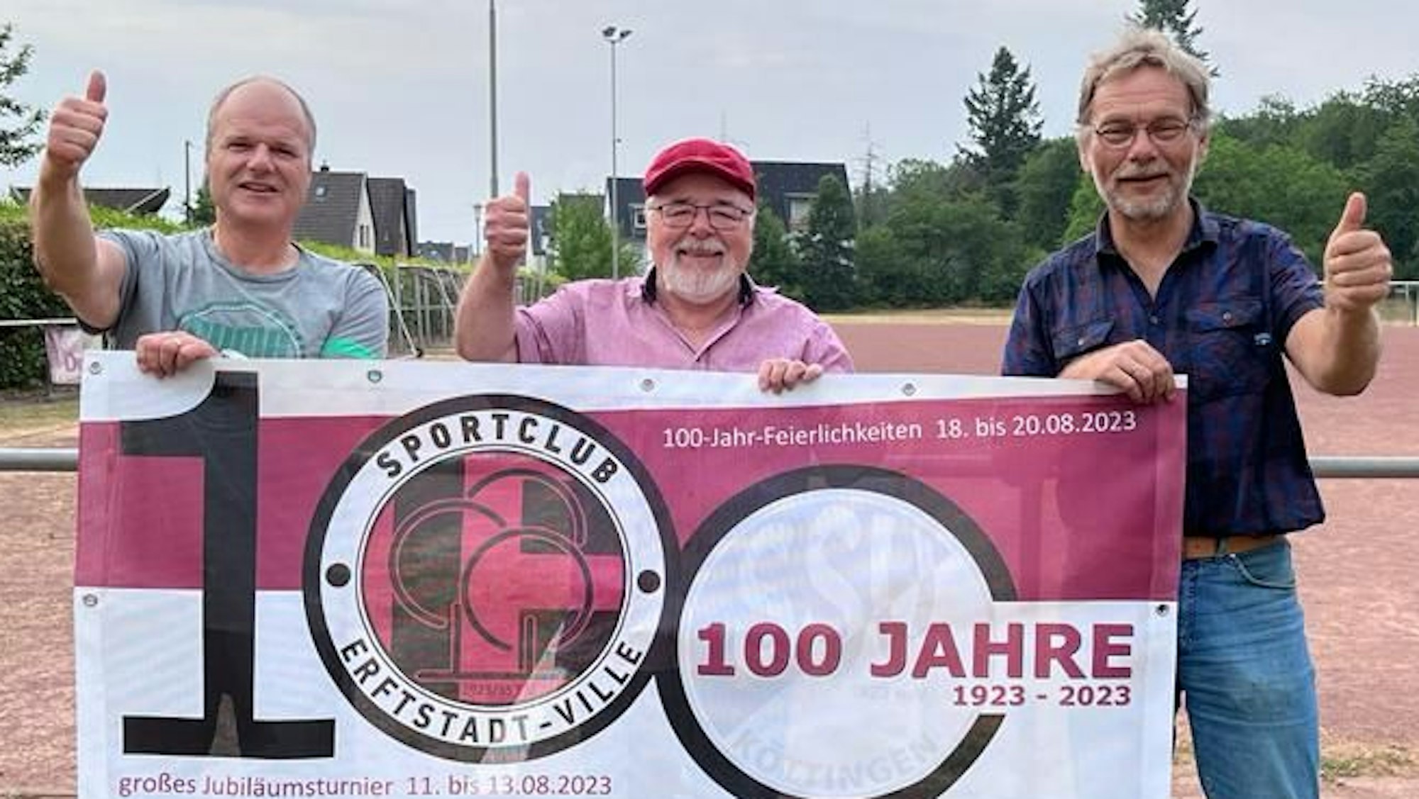 Das Bild zeigt drei Verantwortliche des Vereins. Sie halten ein Banner mit den Logo des Klubs und strecken die Daumen nach oben.