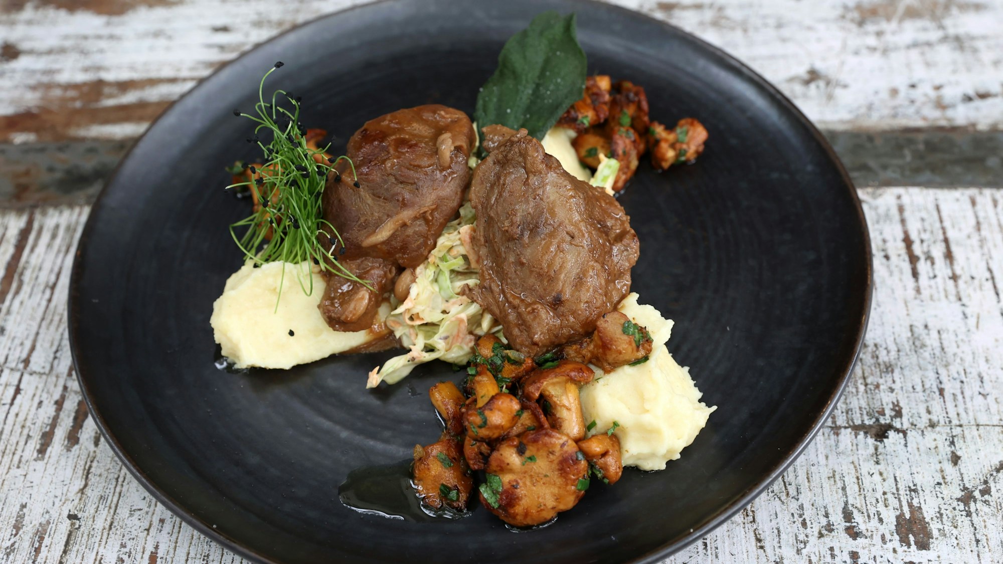 Schweinebacke mit Pfifferlingen und Coleslaw
auf einem Teller auf einem Tisch