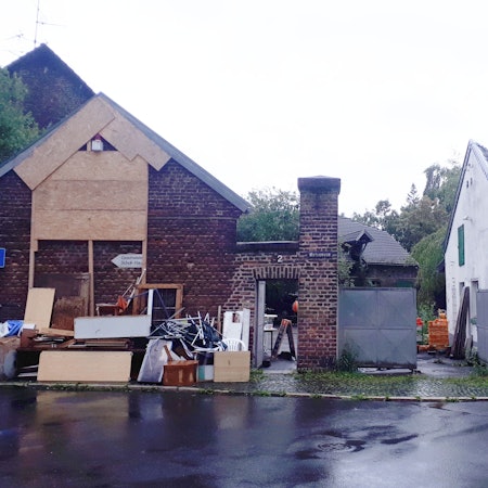 Sperrmüll und Bretter stehen vor einer alten rot verklinkerten Hofanlage.