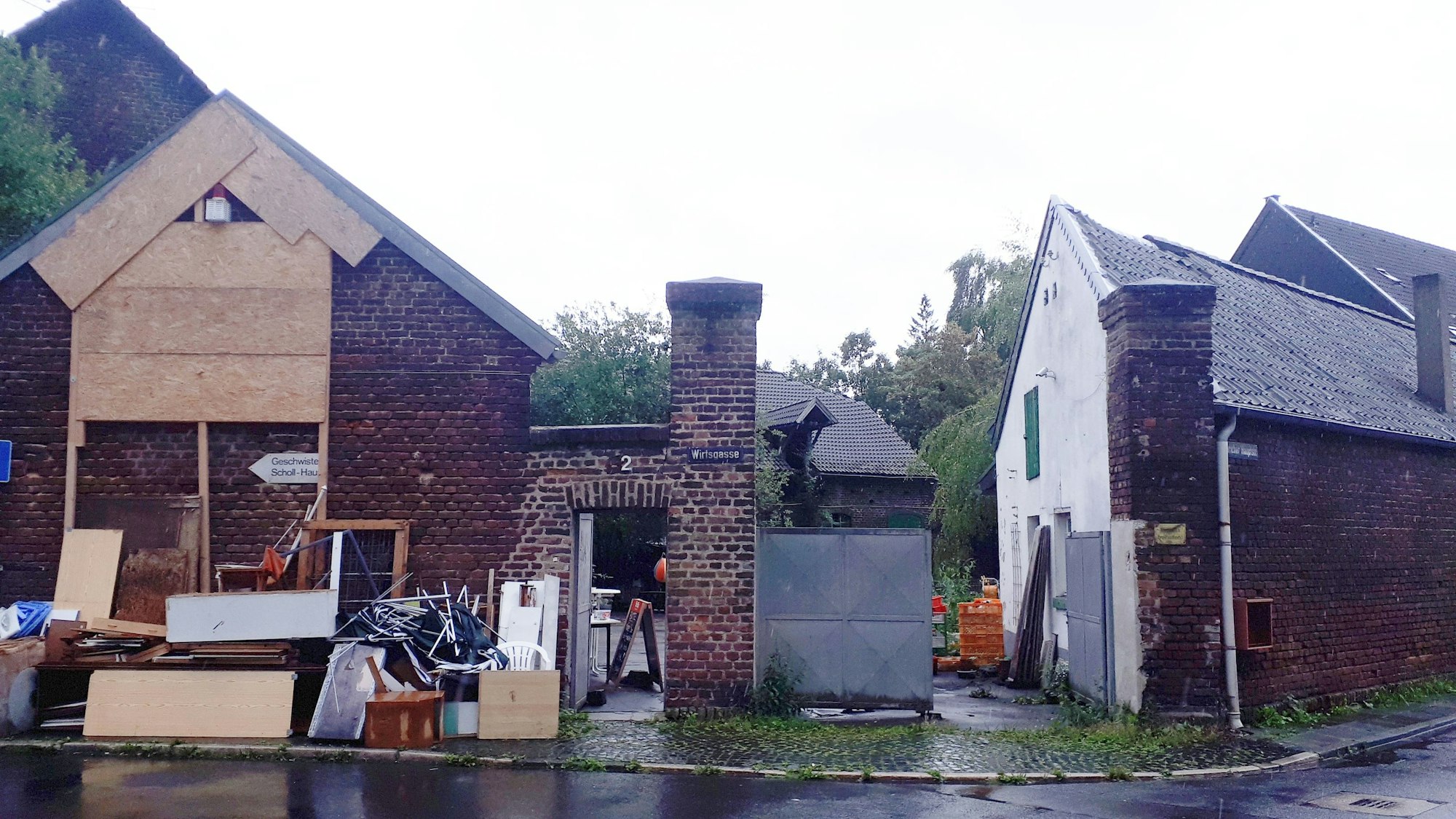 Sperrmüll und Bretter stehen vor einer alten rot verklinkerten Hofanlage.