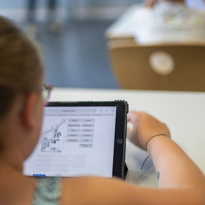 Ein Mädchen sitzt vor einem Tablet.