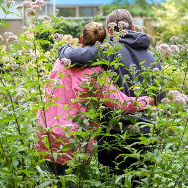Svanja und Johann stehen in einem Garten, sie stehen mit dem Rücken zur Kamera und haben je einen Arm umeinander gelegt.