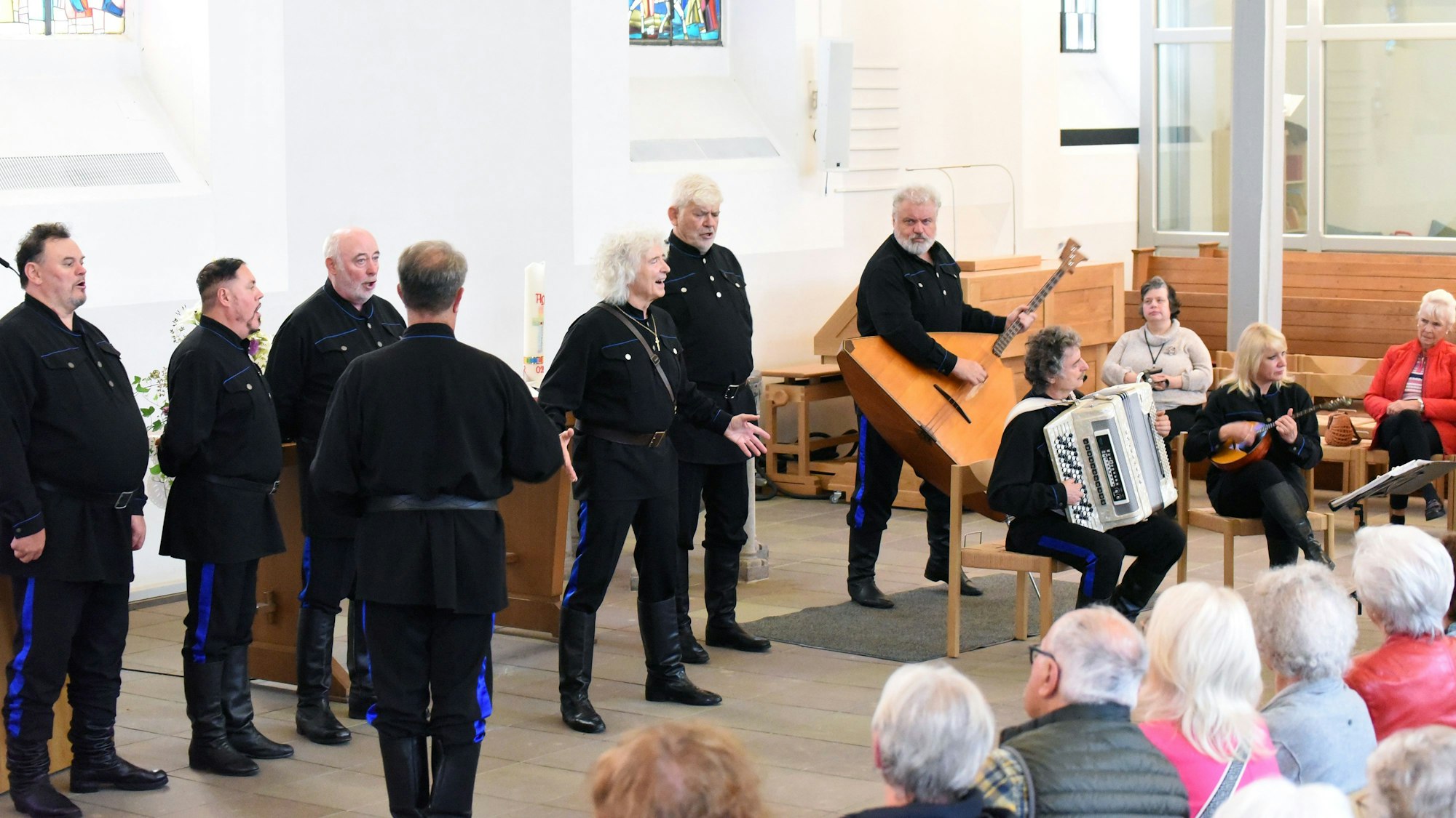 Schwarz gekleidete Sänger und Musiker treten vor Publikum in der Wiehler Kirche auf.