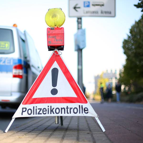 Ein Schild mit der Aufschrift Polizeikontrolle steht vor einem Einsatzwgen der Polizei