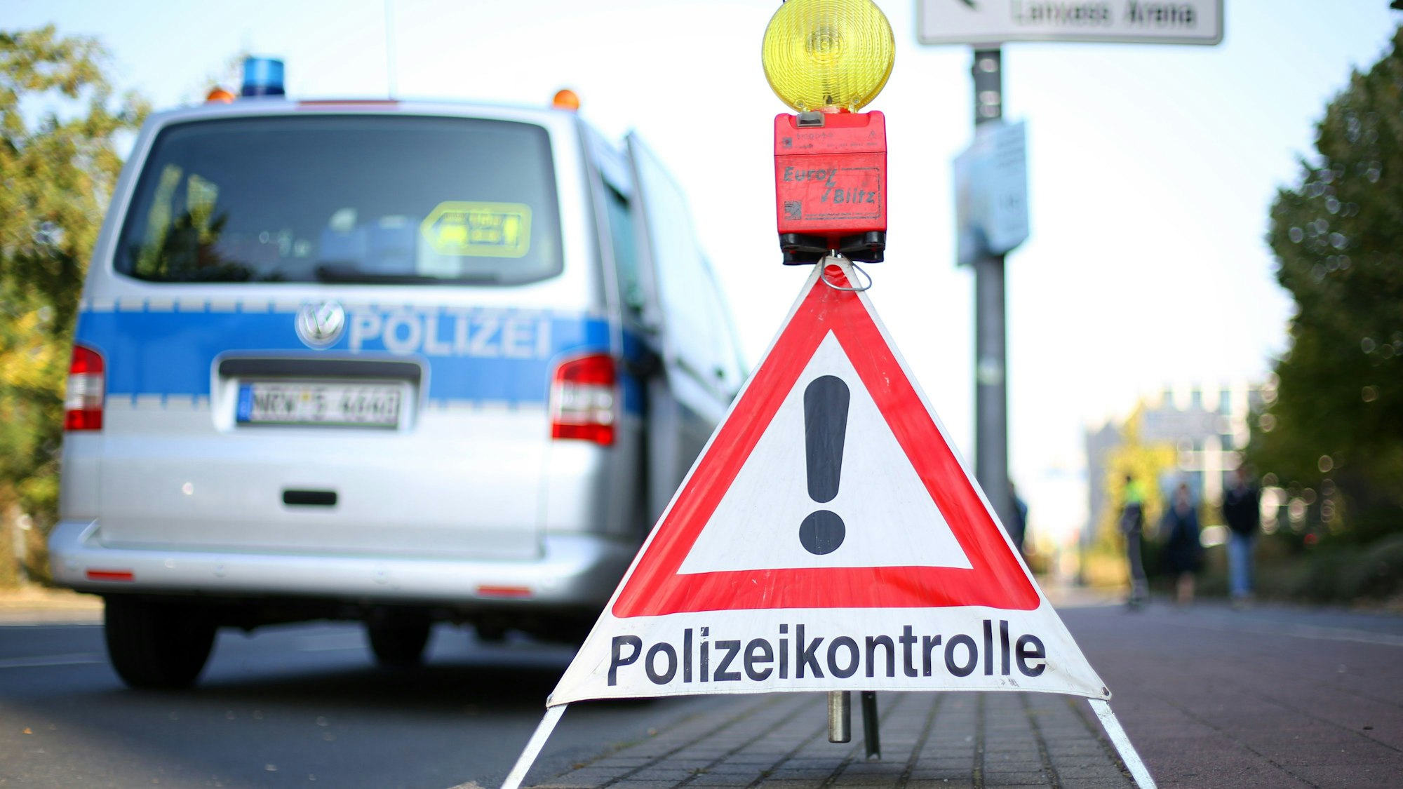 Das Bild zeigt eine Polizeikontrolle mit Polizeifahrzeug im Hintergrund.