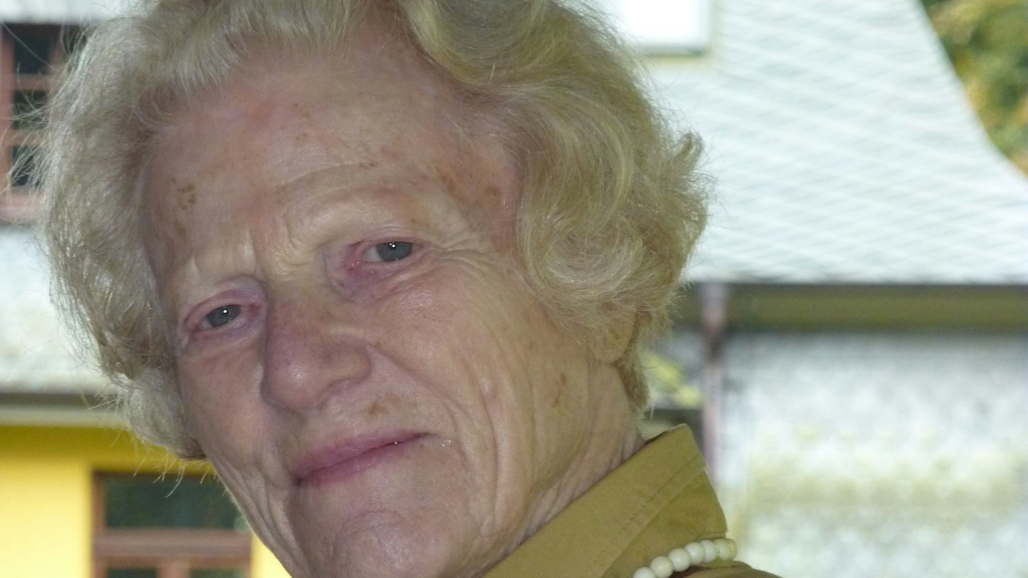 Eine ältere Frau blick in die Kamera.