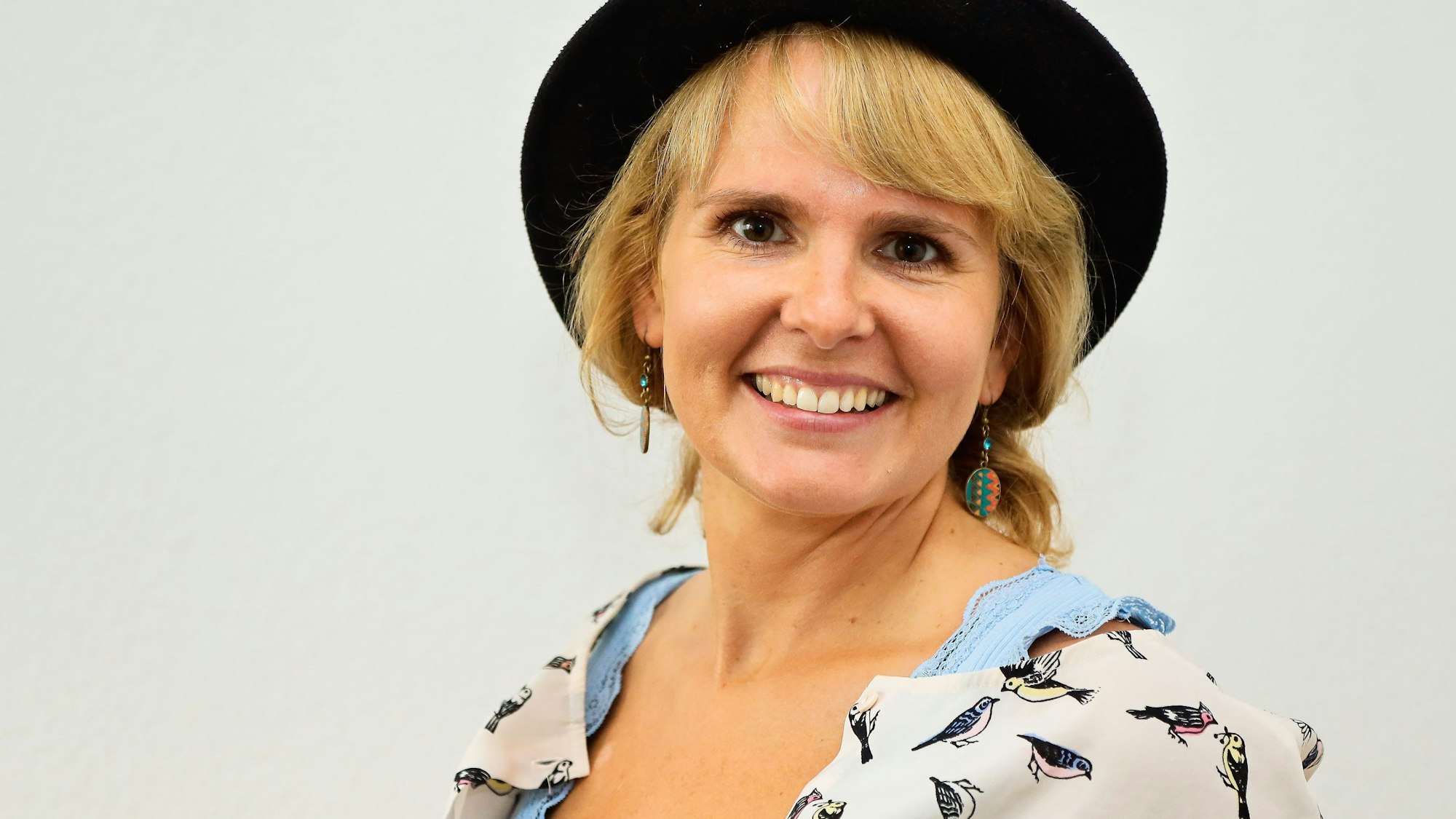 Das Foto zeigt eine blonde Frau mit schwarzem Hut.