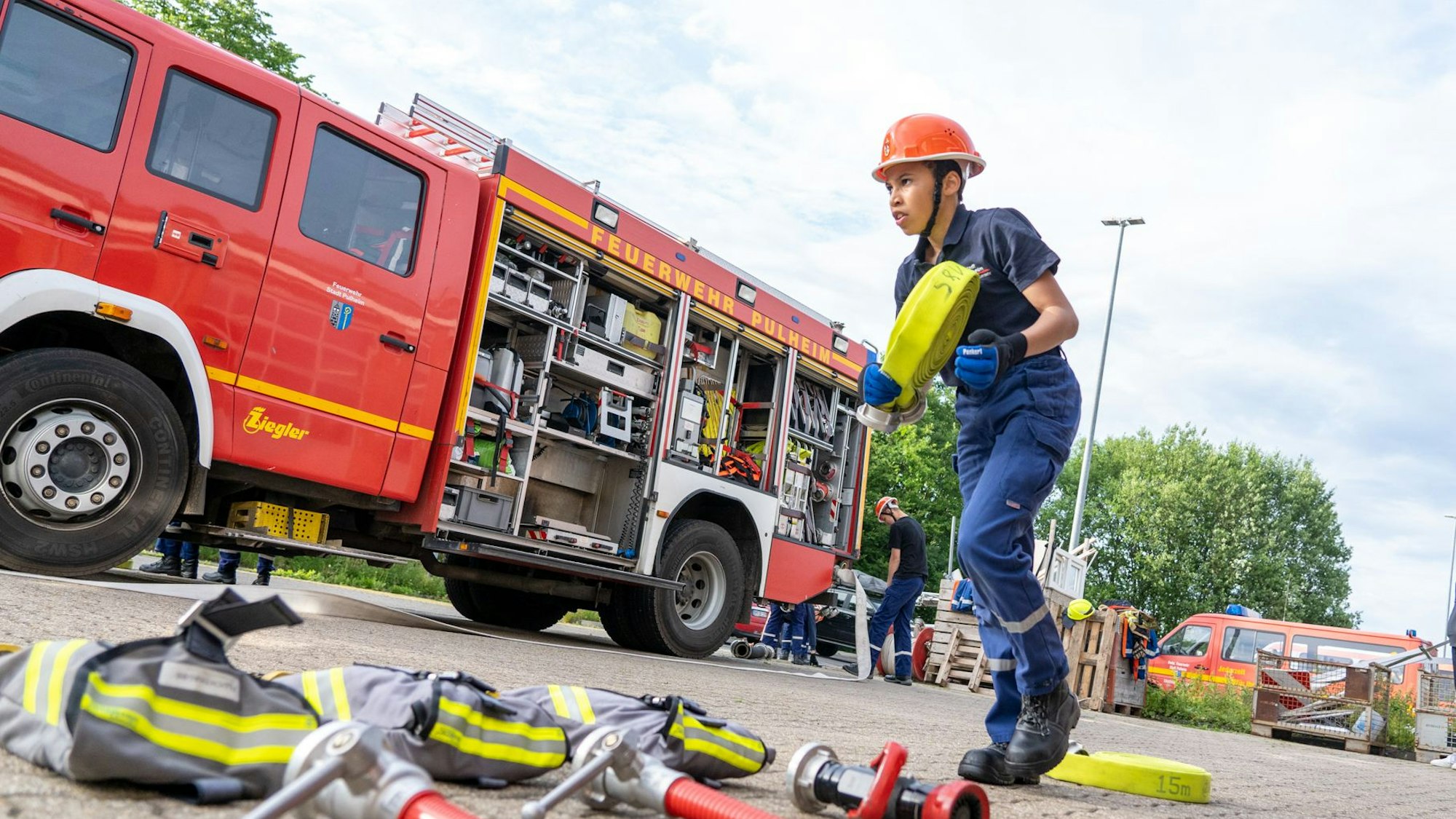 Ein Junge läuft mit einem an einem Einsatzwagen der Feuerwehr vorbei.