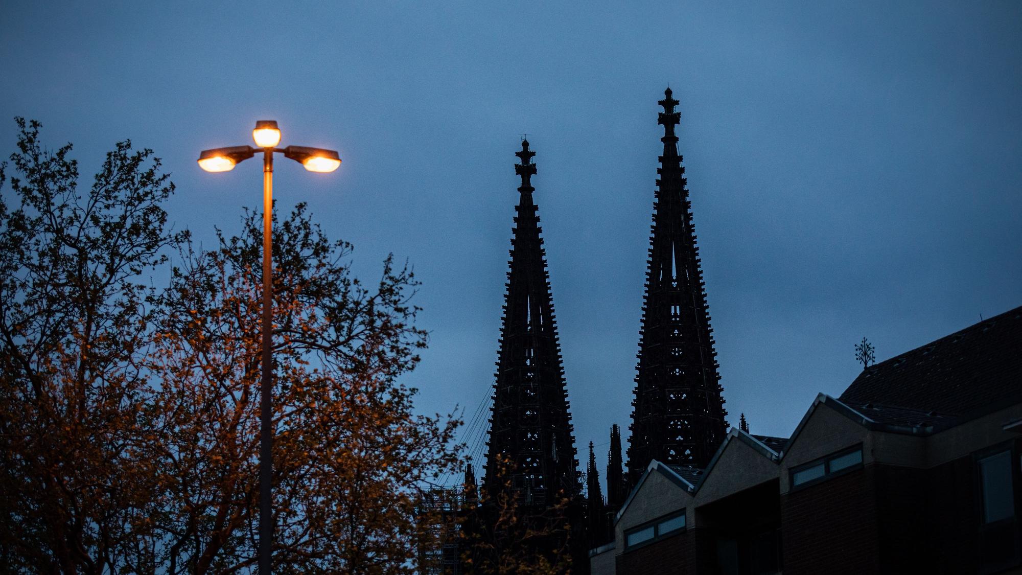 Spitzen des Kölner Dom sind hinter einer leuchtenden Straßenlaterne zu sehen