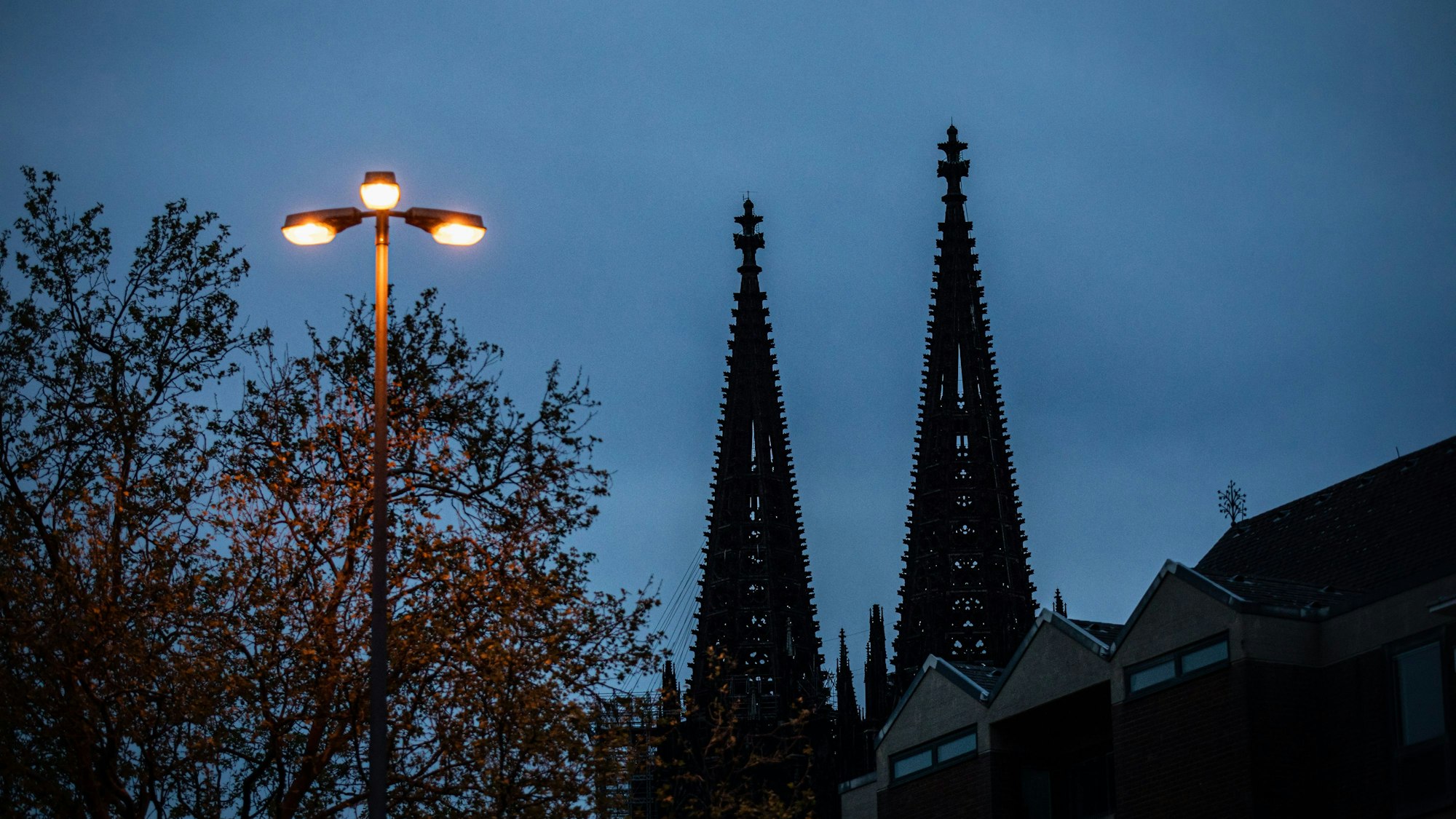 Spitzen des Kölner Dom sind hinter einer leuchtenden Straßenlaterne zu sehen
