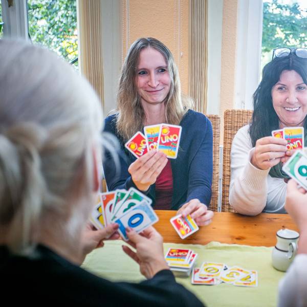 Im Psychosozialen Zentrum in Waldbröl sitzen die Gruppenleiterinnen Sarah Labisch (links) und Dagmar Titze an einem Tisch und spielen Karten mit psychisch beeinträchtigten Menschen, die einen geschützten Raum für den Austausch und Geselligkeit suchen.