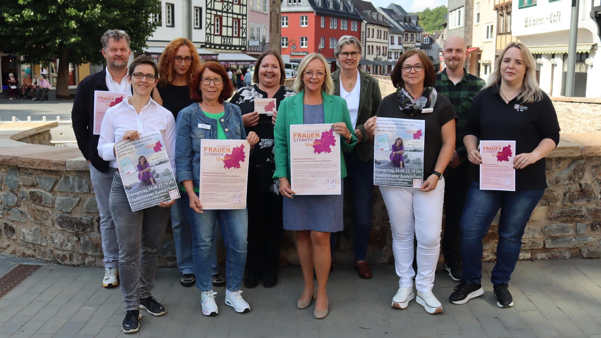 Die Organisatoren der Frauen-Stärken-Wochen und Schirmherrin Sabine Preiser-Marian stehen auf einer Brücke in Bad Münstereifel und präsentieren das Programm.